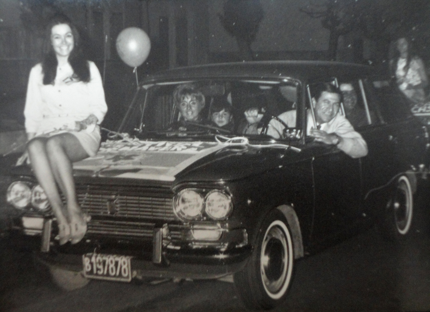 Pablo Frecero de Perfumerí­a Karina lleva a la reina de la primavera en el capót de de su auto.